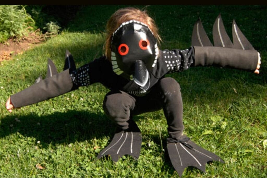 Child wearing a completed homemade loon bird costume on a green lawn