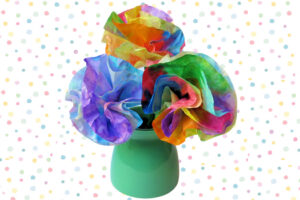 Bouquet of rainbow colored tie-dye coffee filter flowers in a green vase on polka dot background