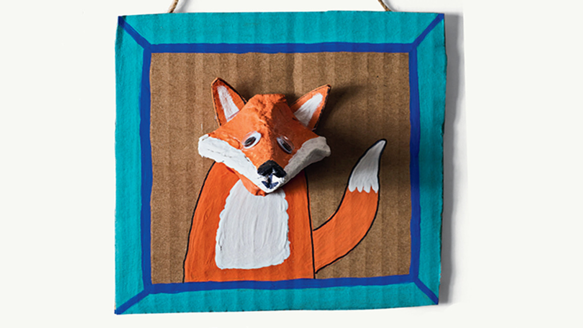 Egg carton fox critter art with painted orange fox head popping out of cardboard frame