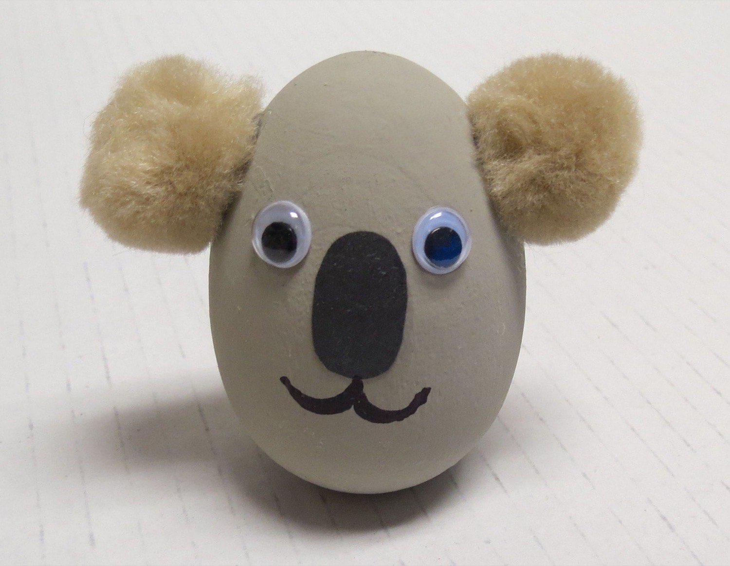 Gray painted wooden egg koala with fuzzy tan pom pom ears googly eyes and black nose
