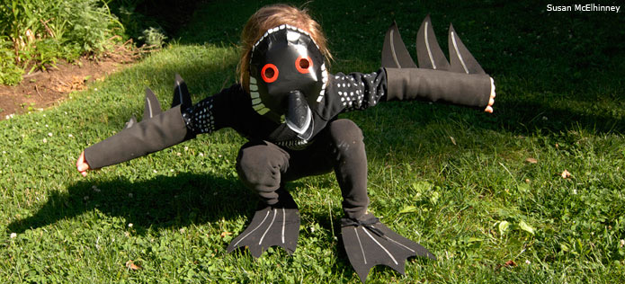 Child wearing a completed homemade loon bird costume on a green lawn
