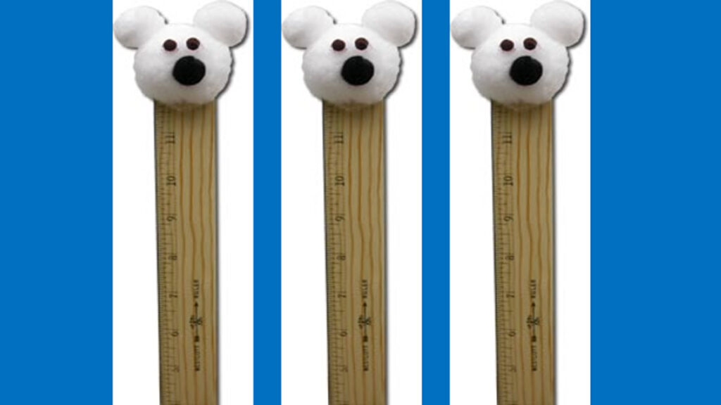 Three polar bear snow gauge crafts with cotton ball heads on wooden rulers on blue background