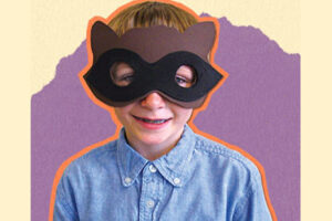 Smiling child wearing a handmade brown paper raccoon mask with black eye band