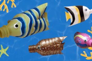 Four colorful tropical fish made from recycled plastic bottles on blue water background