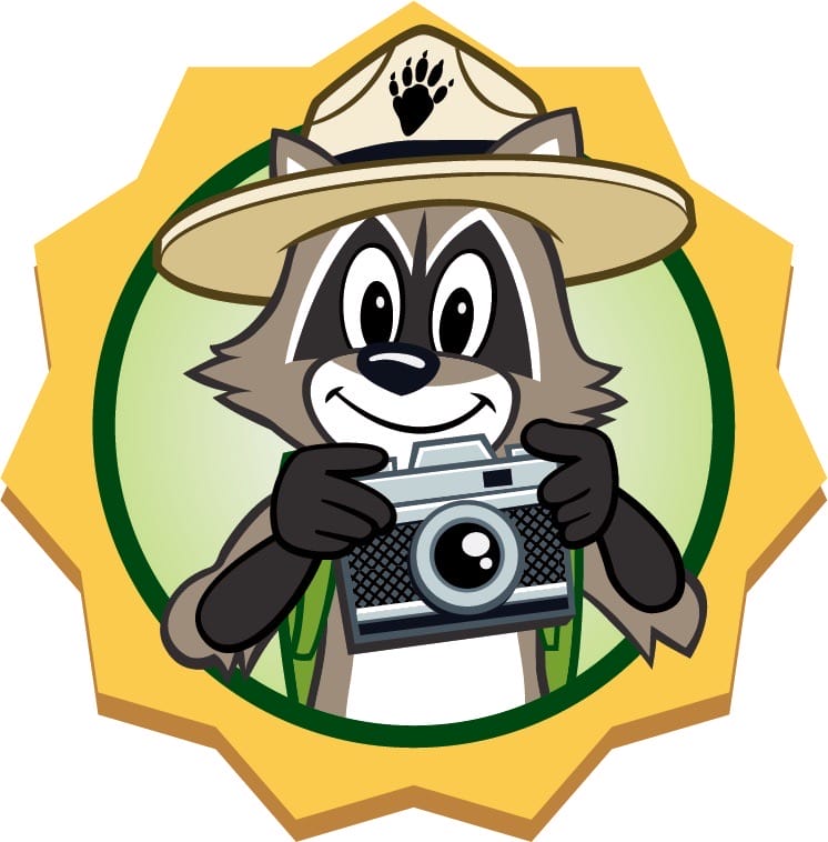Ranger Rick raccoon mascot in ranger hat holding a camera inside a gold badge emblem