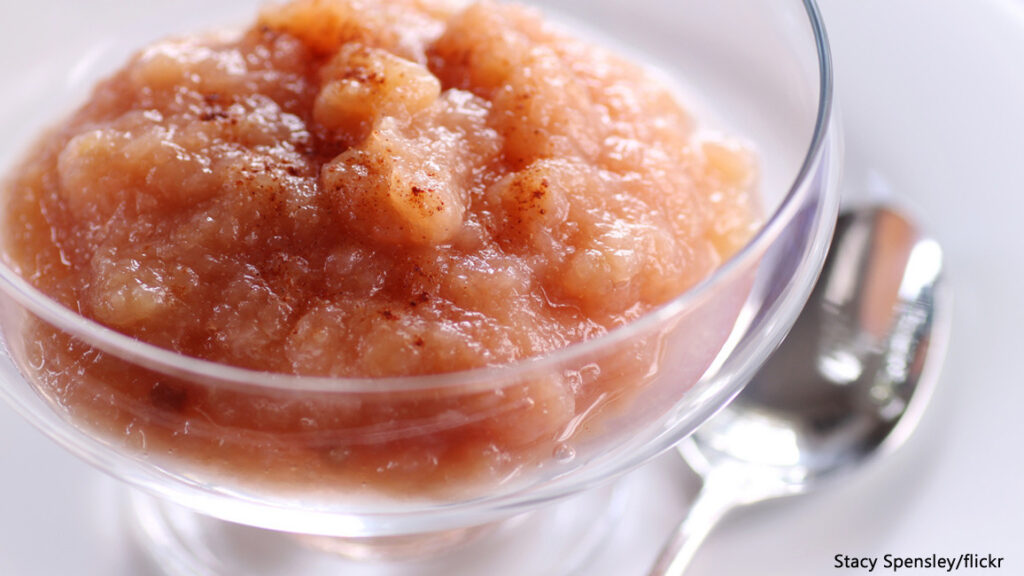Homemade cinnamon applesauce served in a glass dessert bowl with a spoon