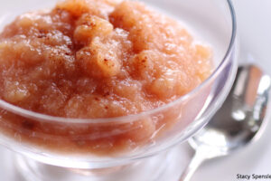 Homemade cinnamon applesauce served in a glass dessert bowl with a spoon