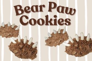 Three chocolate bear paw cookies with almond sliver claws on a striped background
