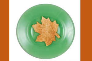 Maple leaf shaped cinnamon sugar cookie on a green plate