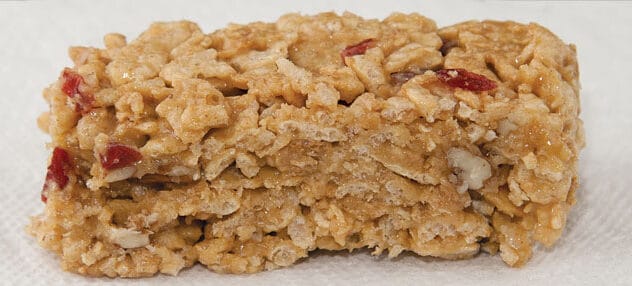 Closeup of a homemade granola breakfast bar with dried cranberries on a white napkin