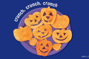 Tortilla chips cut and arranged into smiling jack-o-lantern pumpkin faces on a purple plate
