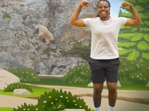 Image of young person dancing next to video screen of a goat climbing a mountain