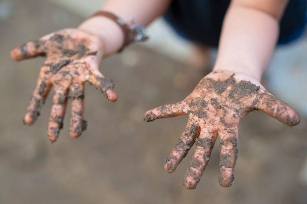 Child's muddy hands for an Earth Day play-in-the-dirt activity