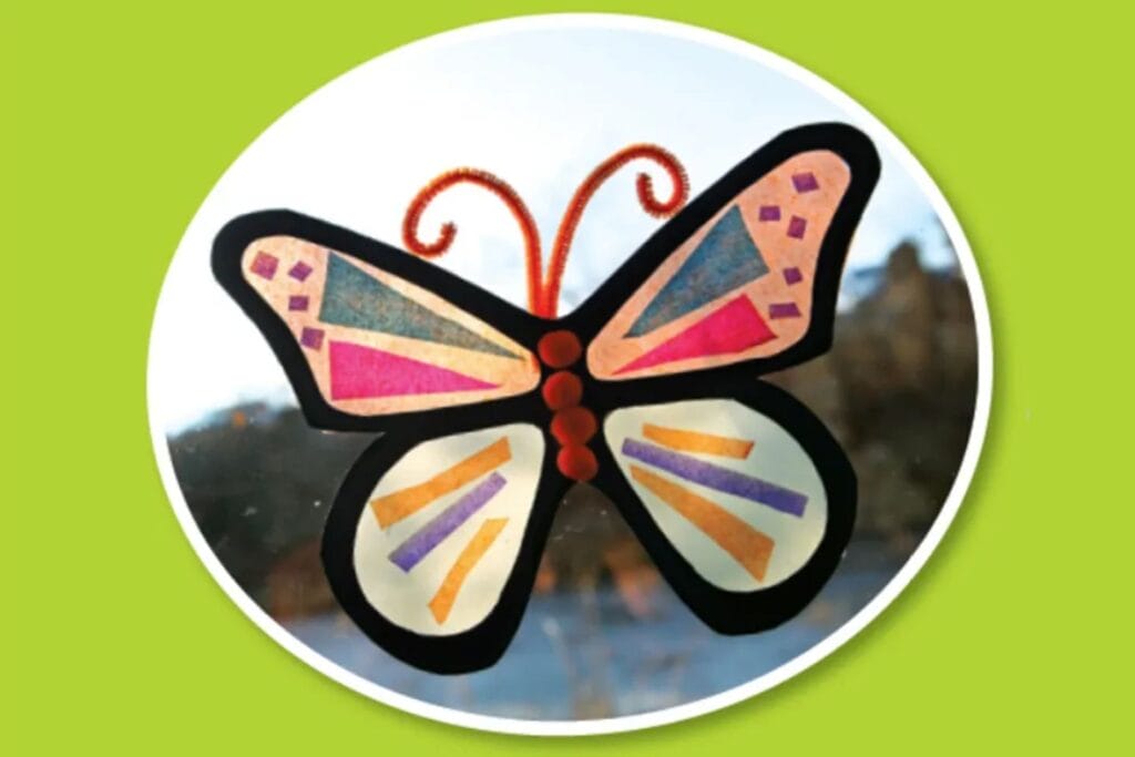 Colorful butterfly sun catcher made from black paper and tissue paper hanging in a window
