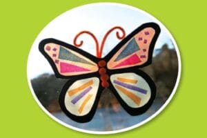 Colorful butterfly sun catcher made from black paper and tissue paper hanging in a window