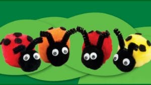Four colorful handmade pom pom ladybugs with googly eyes on green leaf background