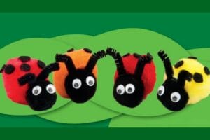 Four colorful handmade pom pom ladybugs with googly eyes on green leaf background