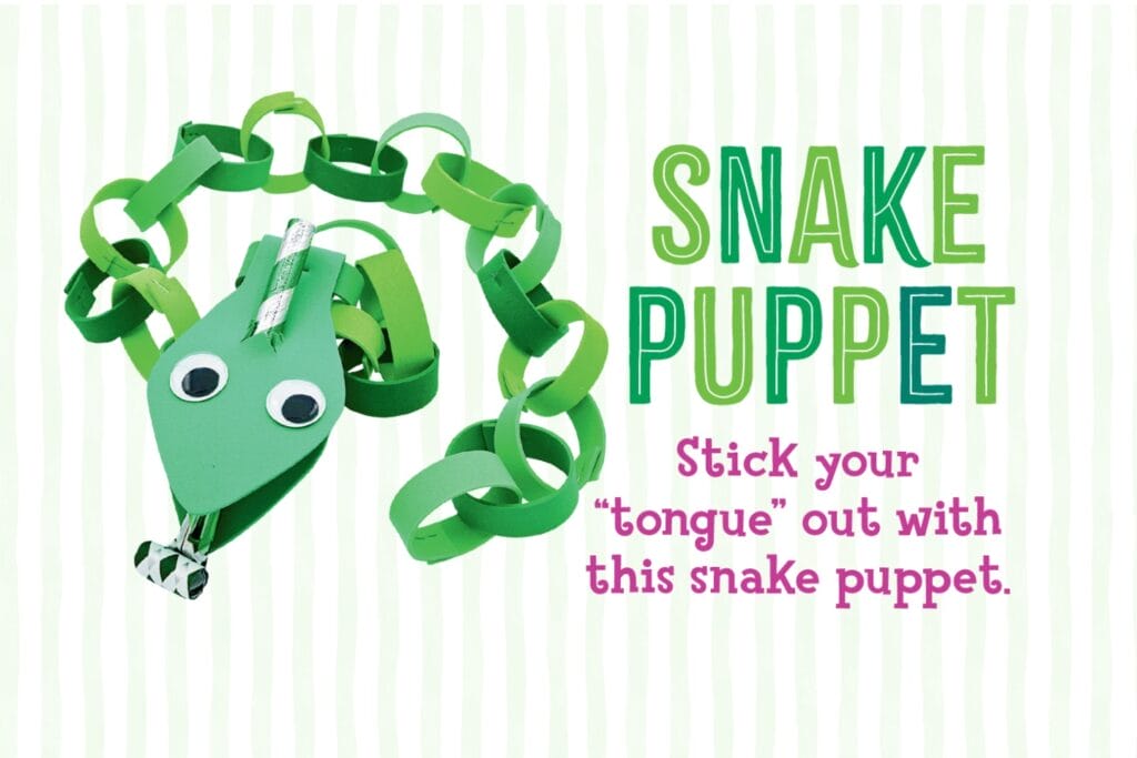Girl blowing a party horn snake tongue while holding up a green paper chain snake puppet