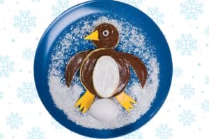 pancake shaped like a penguin with coconut snow on a blue plate